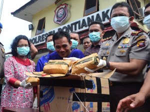 SENYUM TERUS. Polresta Pontianak memusnahkan ganja seberat 16 Kg. Tersangka pembawa barang haram itu (baju biru paling depan), Een, tampak tersenyum terus saat ganja yang ia bawa digelar untuk dimusnahkan di halaman Mapolresta Pontianak, Jumat (18/12). OCSYA ADE CP