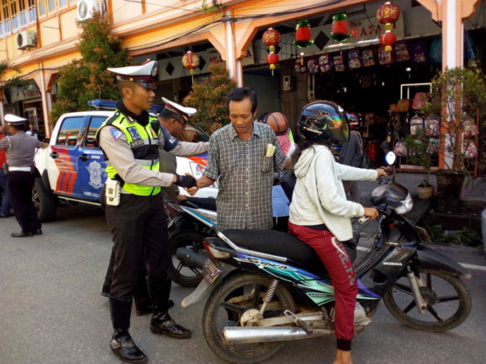 OPERASI KEMANUSIAAN. Anggota Sat Lantas Polres Singkawang ketika mempersilakan pengendara yang tak lengkap dengan alat keselamatan melanjutkan perjalanan di Jalan Sejahtera, Kamis (8/3) pagi—Suhendra/RK