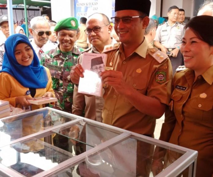 BUKA KEGIATAN. Didampingi Tjhai Chui Mie dan Wakil Walikota Singkawang Irwan menunjukkan salah satu buku di stand Singkawang Book Fair 2018, Senin (12/3)—Suhendra/RK