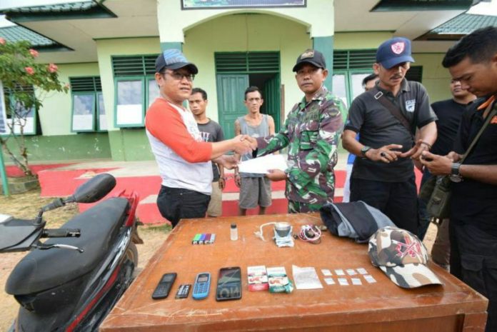 TERSANGKA. Anggota Satgas Pamtas Yonif 123/Rajawali tengah menunjukkan barang bukti dan tersangka kasus narkoba--Pendam for RK