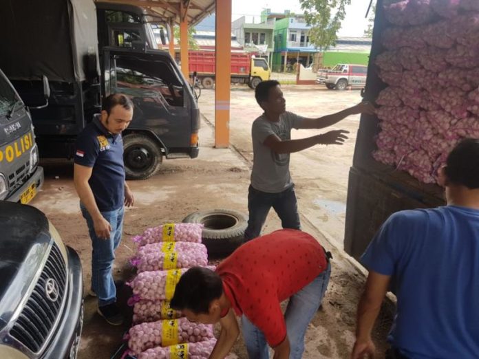 PERIKSA. Petugas tengah memeriksa bawang putih asal Malaysia yang diamankan di depan Mapolsek Sanggau Ledo, Minggu (1/4)--Kurnadi/RK