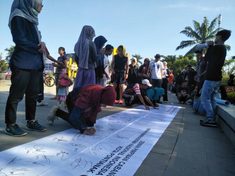 TANDA TANGAN. Warga menandatangani Deklarasi Pilkada Damai di kain putih sepanjang lima meter di kawasan Digulis Untan Pontianak, Minggu pagi (22/4). Gusnadi-RK