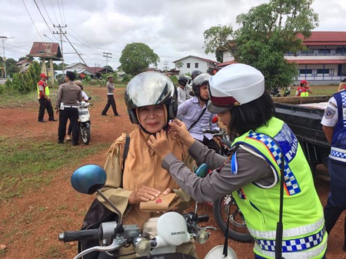 TEGUR. Polwan dari Sat Lantas Polres Kapuas Hulu mencontohkan pemasangan helm dengan benar kepada salah satu pengendara yang diberi teguran dalam Operasi Patuh Kapuas 2018, belum lama ini--Polisi for RK