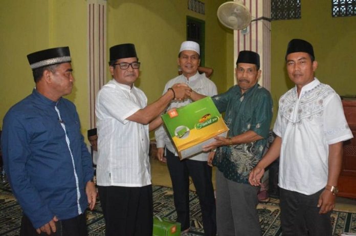 Ketua DPRD Melawi, Abang Tajudin menyerahkan bingkisan kepada Ketua Masjid At Taqwa Desa Manggala, Kecamatan Pinoh Selatan, Unun Supiyatna.