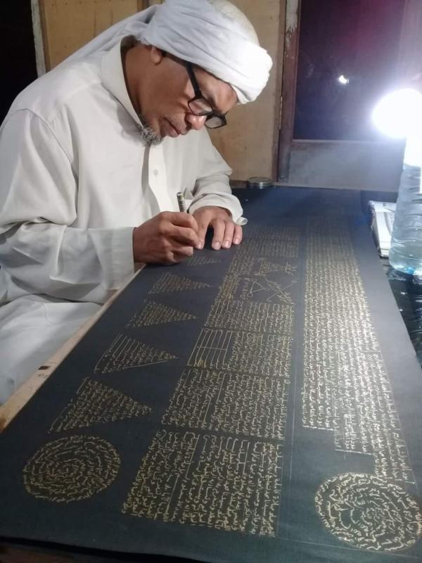 MENULIS AYAT ALQURAN. Usman Khalid sedang menyelesaikan rajah ayat suci Alquran di sebuah kertas di rumahnya, Desa Langko, Kecamatan Lingsar, Lobar. Lombok Pos Photo