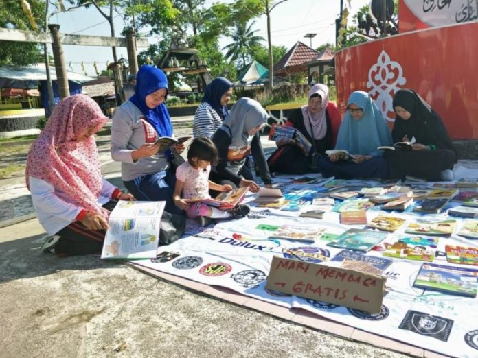 ANTUSIAS. Masyarakat dengan antusias membaca buku yang digelar Komunitas Membaca dan Perpustakaan Jalanan Singkawang di Jalan Merdeka, Singkawang, Minggu (22/7)—SUHENDRA/RK