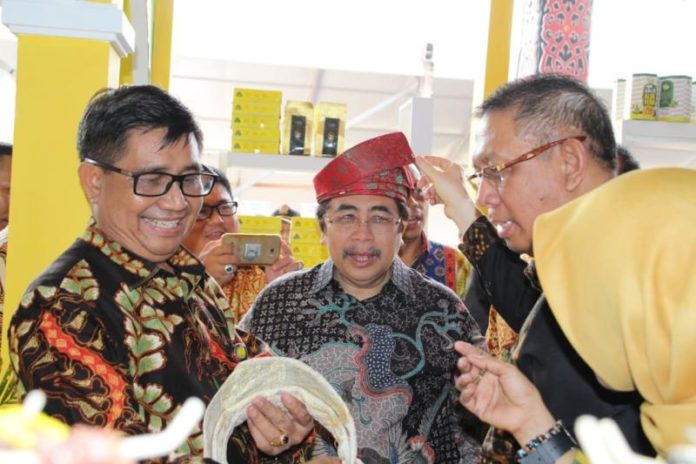 TANJAK. Pj Gubernur Kalbar Dodi Riyadmadji menggunakan tanjak yang diberikan langsung oleh Wali Kota Pontianak Sutarmidji di stand Kota Pontianak di pembukaan Pameran Pesparawi Nasional ke XII Tahun 2018 di Rumah Radakng, Pontianak, Sabtu (28/7). Humas Pemkot for RK.