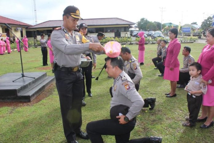 NAIK PANGKAT. Kapolres Kapuas Hulu AKBP Imam Riyadi melakukan prosesi penyiraman air kembang kepada personel yang mendapat kenaikan pangkat di Halaman Mapolres Kapuas Hulu, Sabtu (30/6)—Andreas/RK