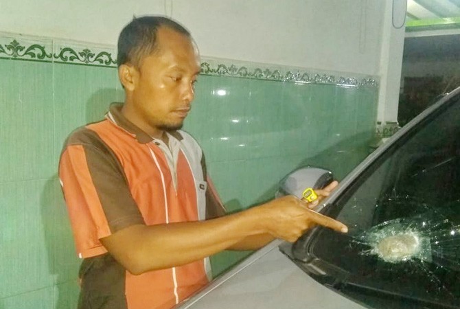 RUSAK: Mohammad Johan menunjukkan batu yang masih berada di kaca depan mobil miliknya Senin malam (2/7). (MOHAMMAD JOHAN FOT Radar Madura/JawaPos.com)