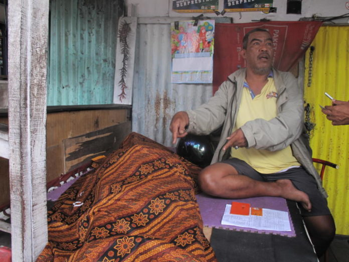 JENAZAH. Seorang warga duduk di samping jenazah Kaspin, lansia yang meninggal di kios milik Ismail, di Jalan Tanjungpura, Pontianak Selatan, Rabu (1/8)--Maulidi Murni.