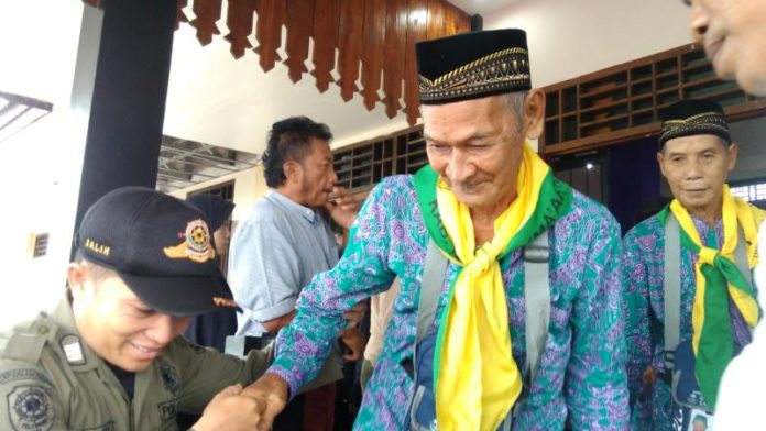 TERTUA. Dibimbing petugas untuk memasuki bus menuju Kota Pontianak, Bujang Abas Daud, warga Desa Galing, Kecamatan Galing, berusia 94 tahun menjadi jemaah calon haji (JCH) tertua se-Kalbar, Selasa (31/7). Sairi-RK