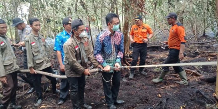 PADAMKAN API. Edi Rusdi Kamtono (berbaju batik) membantu petugas Damkar memadamkan api kebakaran lahan milik Untan Pontianak, Kamis (23/8). Bangun Subekti-RK