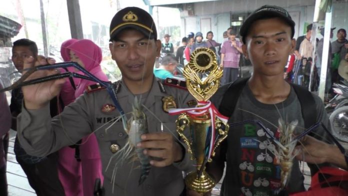 UDANG TERBERAT. Kapolsek Sejangkung, Ipda Wismo Harjanto bersama Juara Lomba Mancing Udang HUT Bhayangkara ke-72, M Kholir yang berhasil mendapatkan udang seberat 3,1 ons, Minggu (29/7). Sairi