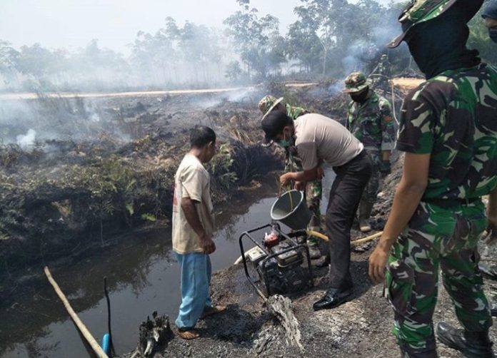 PADAMKAN API. Personel Polres, TNI dan BPBD bahu-membahu bersama masyarakat memadamkan api yang melahap lahan dan hutan di wilayah Kabupaten Mempawah, Senin (20/8).